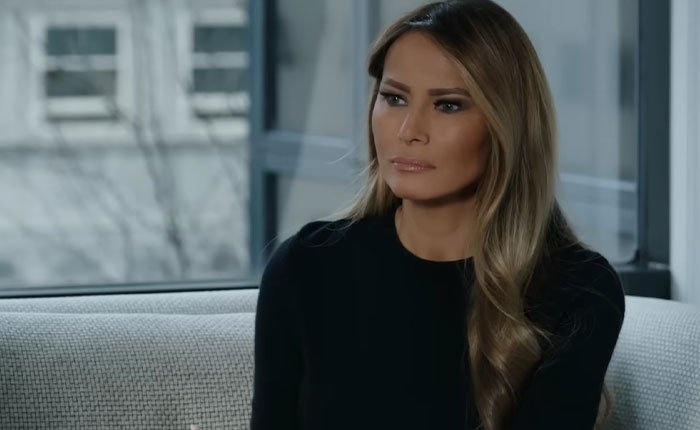 Melania Trump sitting on a couch indoors with a serious expression in her new documentary interview.