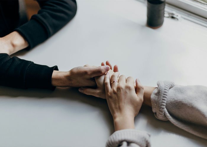 Two people holding hands across a table, representing intimate encounters and K-Drama-style dates concept.