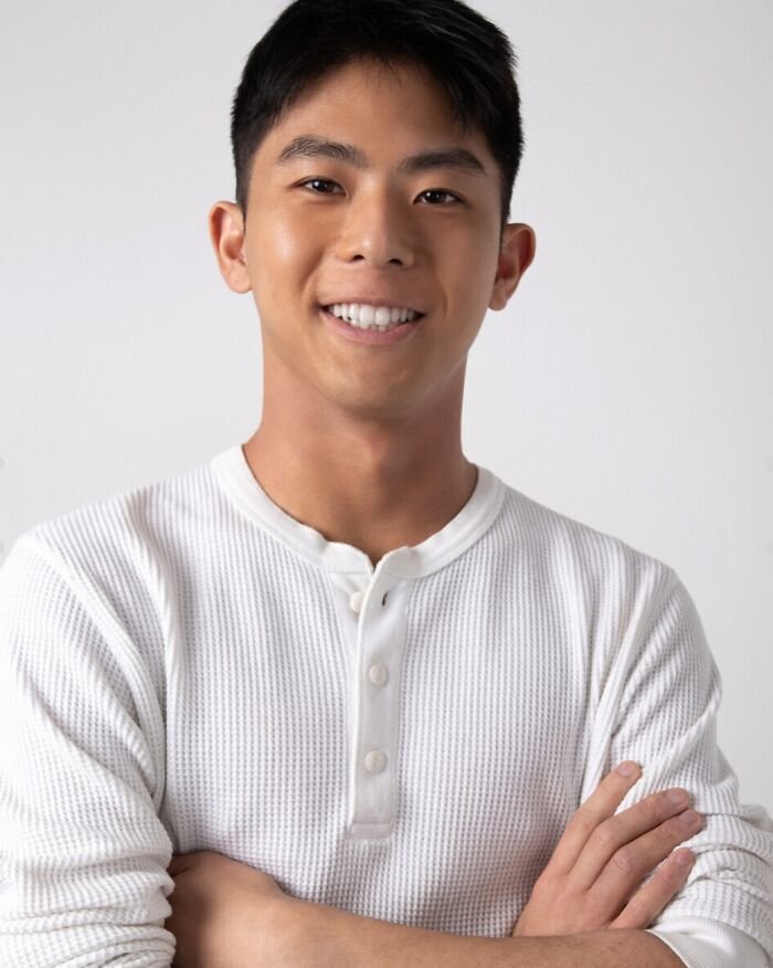 Young Asian man smiling confidently in a white shirt, representing website offering intimate encounters with Koreans and K-drama-style dates.