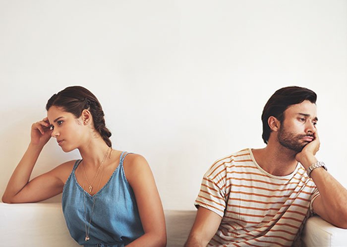 Woman and man sitting apart looking upset, illustrating relationship issues after boyfriend salts entire pot of chili
