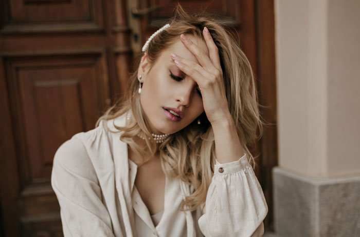 Woman covering her face with hand, looking stressed, representing husband and family call about picky eater allergies.