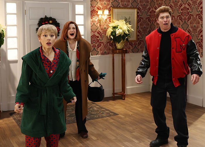 SNL Home Alone parody scene with Ariana Grande and cast reacting in a room with vintage wallpaper and holiday decor.