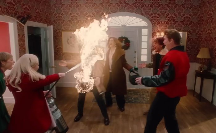 Ariana Grande in SNL Home Alone parody scene using fire extinguisher during chaotic and bloody twist moment indoors.