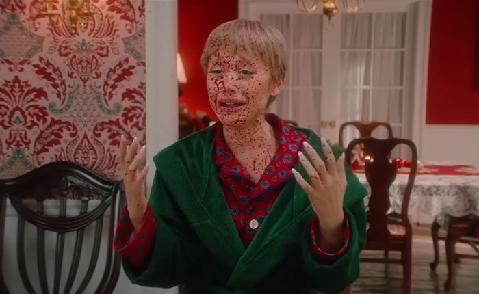 Actor in SNL Home Alone parody with bloody face and green robe, showing shocked expression in dramatic scene.