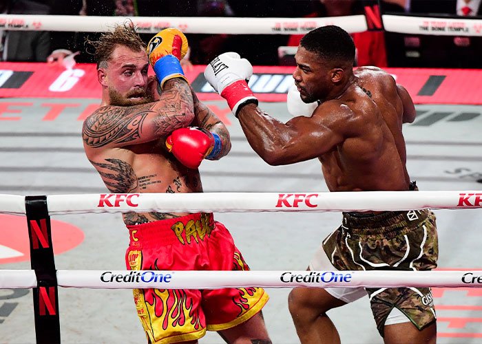 Jake Paul in boxing ring receiving punch, highlighting Jake Paul's broken jaw as internet's latest punchline.