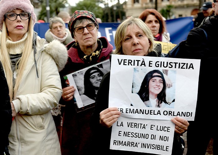 Women holding signs with photos of the Vatican Girl during a gathering for the decades-old cold case investigation.
