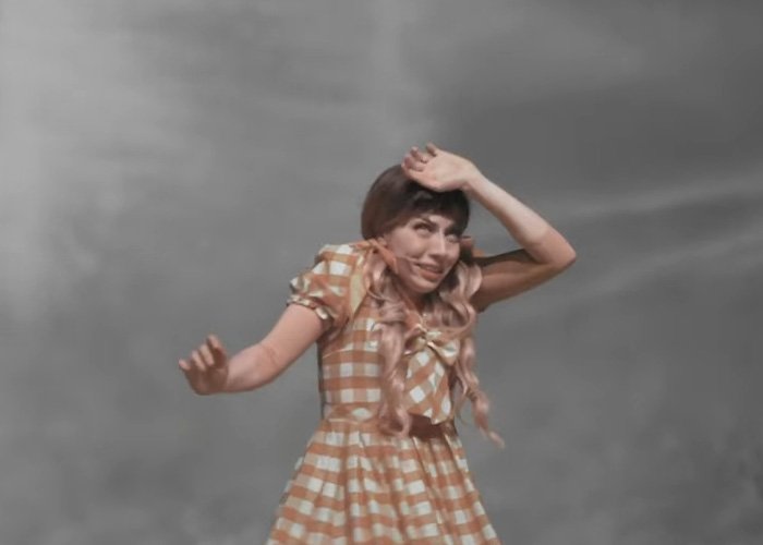Actress in a yellow checkered dress reacting dramatically during a Wizard of Oz performance that outraged the audience.