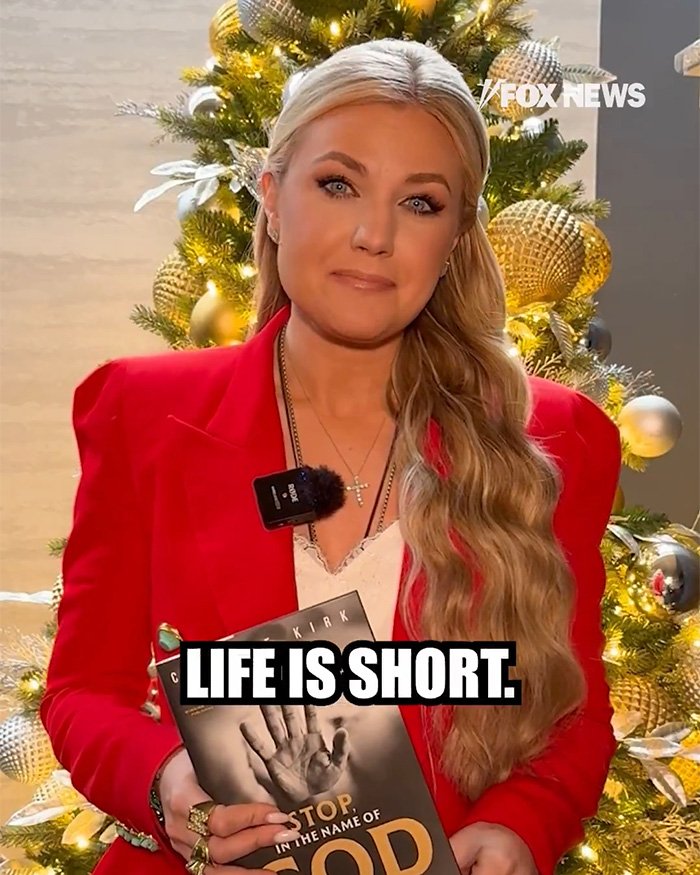 Erika Kirk holding Charlie Kirk&rsquo;s book in front of a decorated Christmas tree during a holiday message.