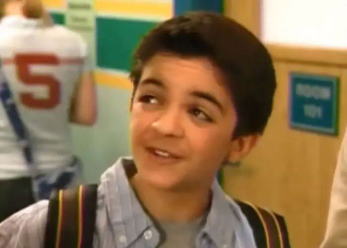 Young Nickelodeon star Tylor Chase smiling in a school hallway, with a backpack over his shoulder.
