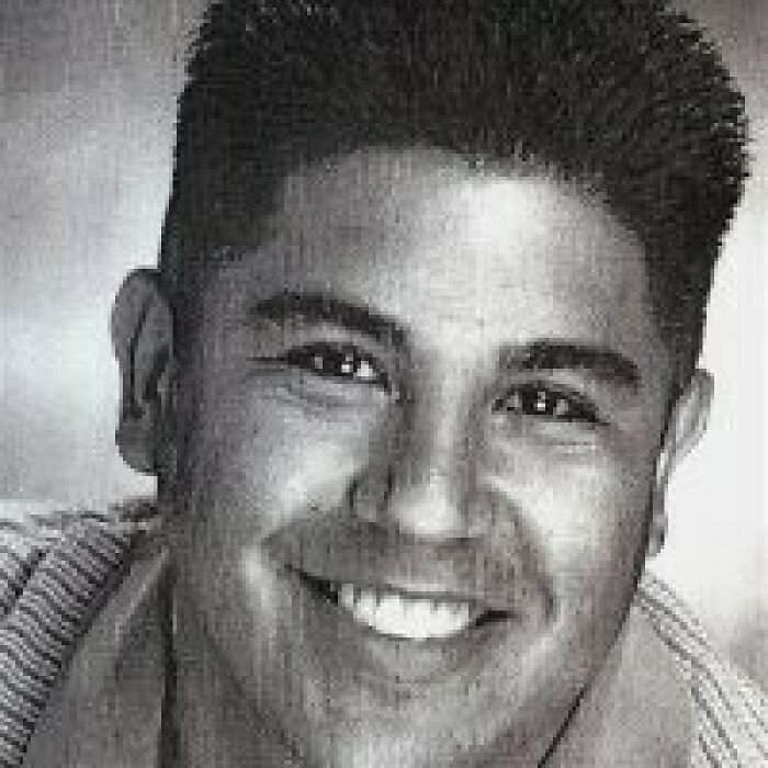 Black and white close-up of dad of Nickelodeon star Tylor Chase smiling in an indoor setting with short dark hair.