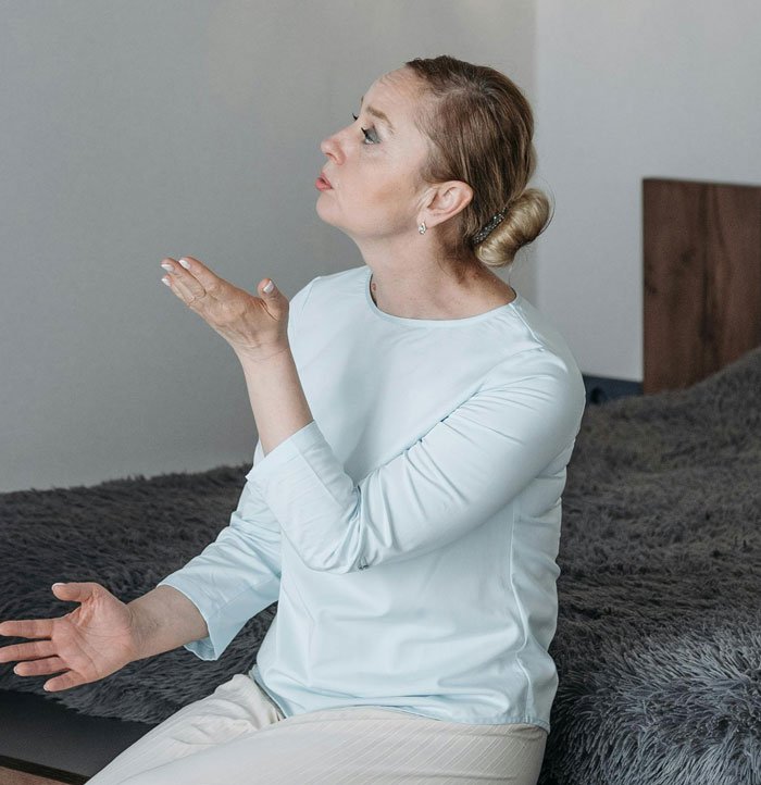 Middle-aged woman sitting on bed expressing frustration and sadness about family issues and emotional struggles.