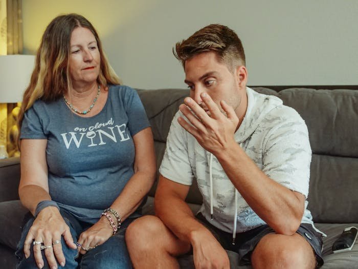 Man and woman seated on a couch in a tense family conversation, reflecting shame guilt and embarrassment.