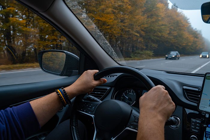Man driving car on a scenic road, symbolizing a guy going above and beyond for his ex girlfriend.