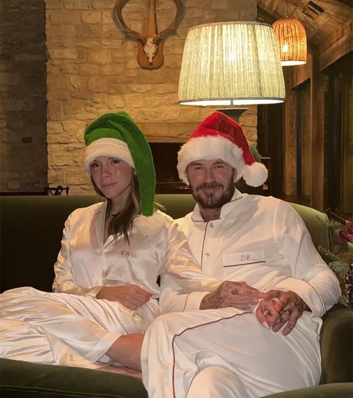 Brooklyn’s wife Nicola Peltz and Victoria wearing festive hats, sitting closely on a couch in holiday pajamas.