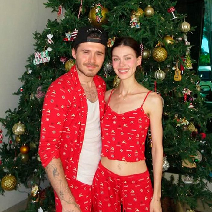 Brooklyn’s wife Nicola Peltz and Victoria posing in matching red pajamas by a Christmas tree.