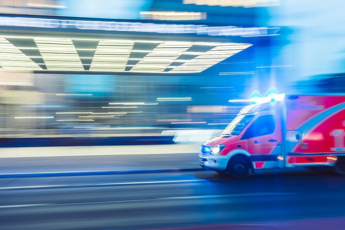 Ambulance rushing at night, representing woman hospitalized after family intervention over obsession with brother.
