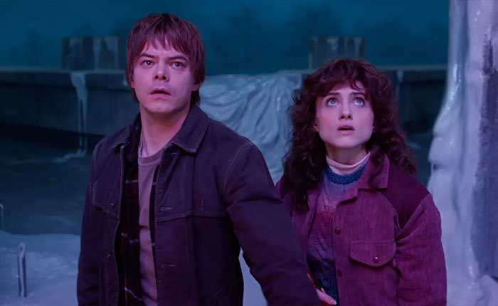 Two Stranger Things 5 characters in a dimly lit icy setting, looking shocked and concerned.