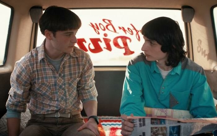 Two Stranger Things 5 characters sit inside a van, having a serious conversation, highlighting the show's comically bad moments.