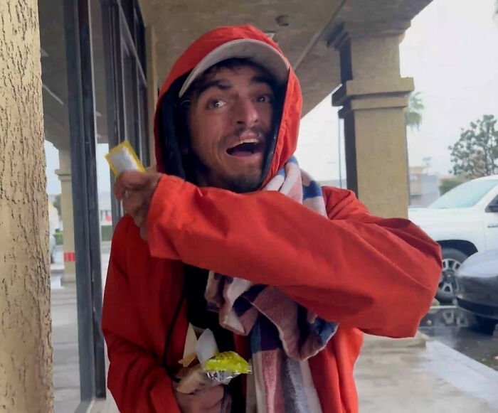 Man in red hoodie and scarf outdoors, holding snacks, linked to Tylor Chase’s hospitalization and friend’s revelation.