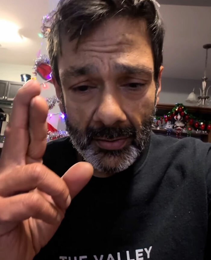 Man with a beard and serious expression raising hand, relating to Tylor Chase’s hospitalization and friend’s revelation.