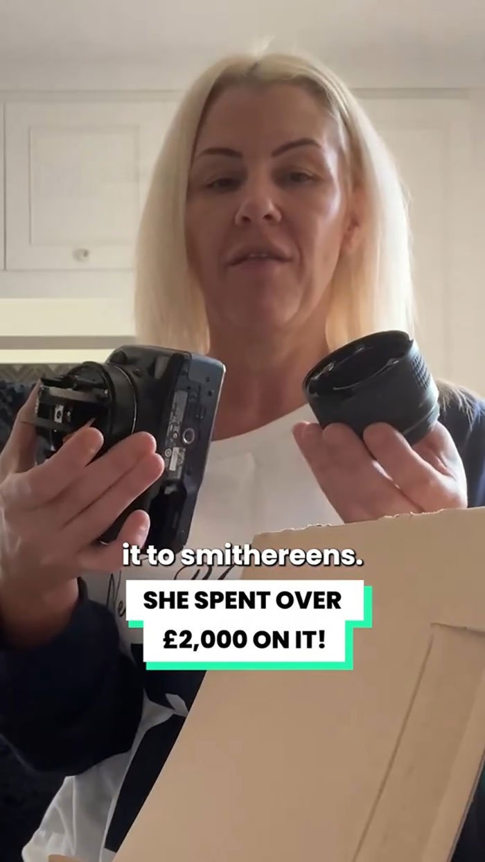 Woman holding broken camera lens and body, claiming Christmas gift was shattered by delivery driver with footage shown.