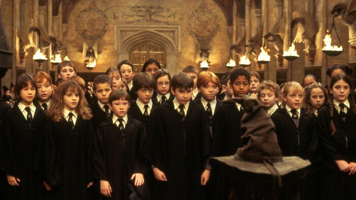 Group of young Hogwarts students in robes standing before the sorting hat during the Harry Potter challenge scene.