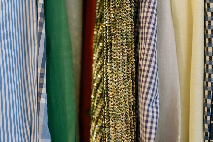Various iconic outfits with sequins and patterned fabrics hanging, related to iconic film fashion from popular movies.