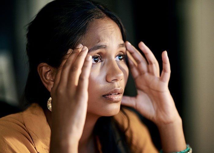 Worried woman holding her head, appearing stressed and trapped, illustrating being held hostage at parents’ place.