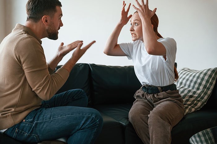 Man and girlfriend having a heated argument on couch after he lends her a spare keyboard, tension rises between the couple.