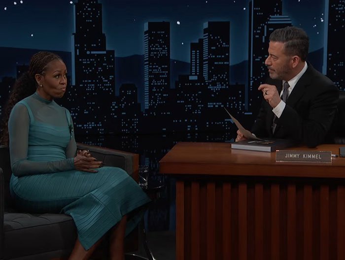 Michelle Obama in a teal dress during a late-night talk show interview discussing recent political controversies.