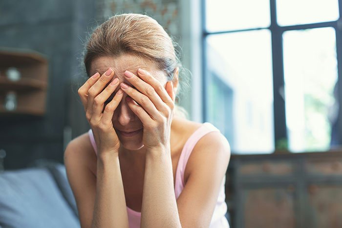 Childfree woman stressed and covering her face, refusing to take responsibility for her sister's new baby.