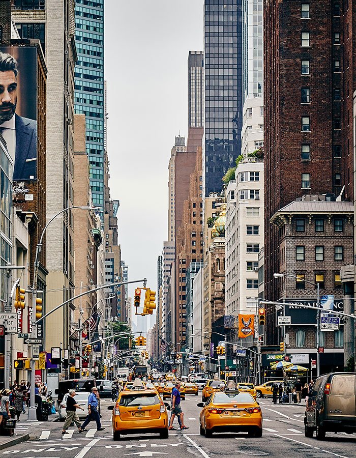 Busy Manhattan street scene with yellow taxis and pedestrians, highlighting a pit bull attack involving a toddler in the crowded area.