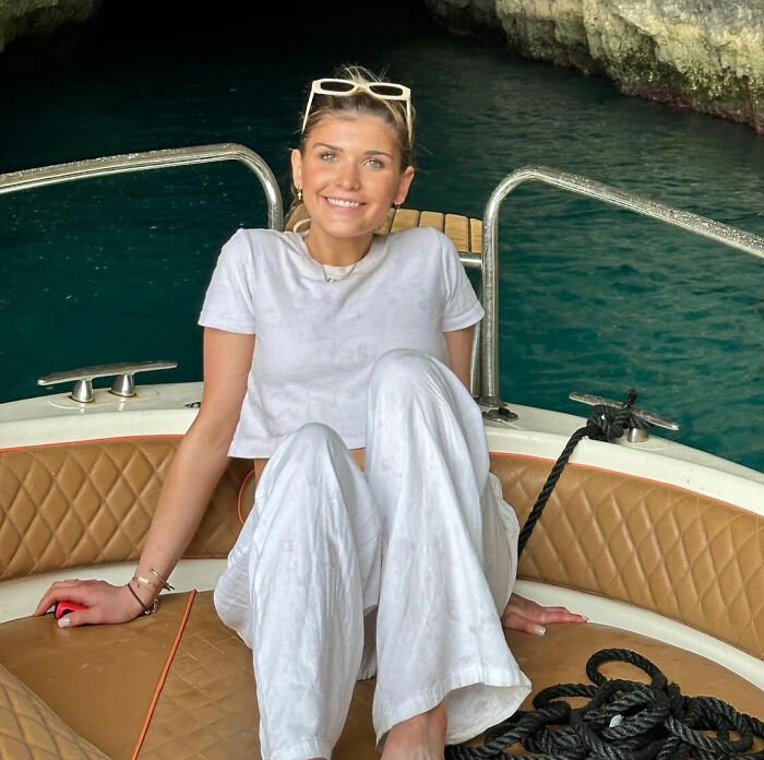 Young sorority girl smiling on a boat near crystal blue water, capturing a serene moment before tragic Christmas Eve accident.