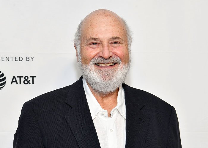 Rob Reiner smiling in a black jacket and white shirt at a media event, related to Trump controversy over TDS claims.
