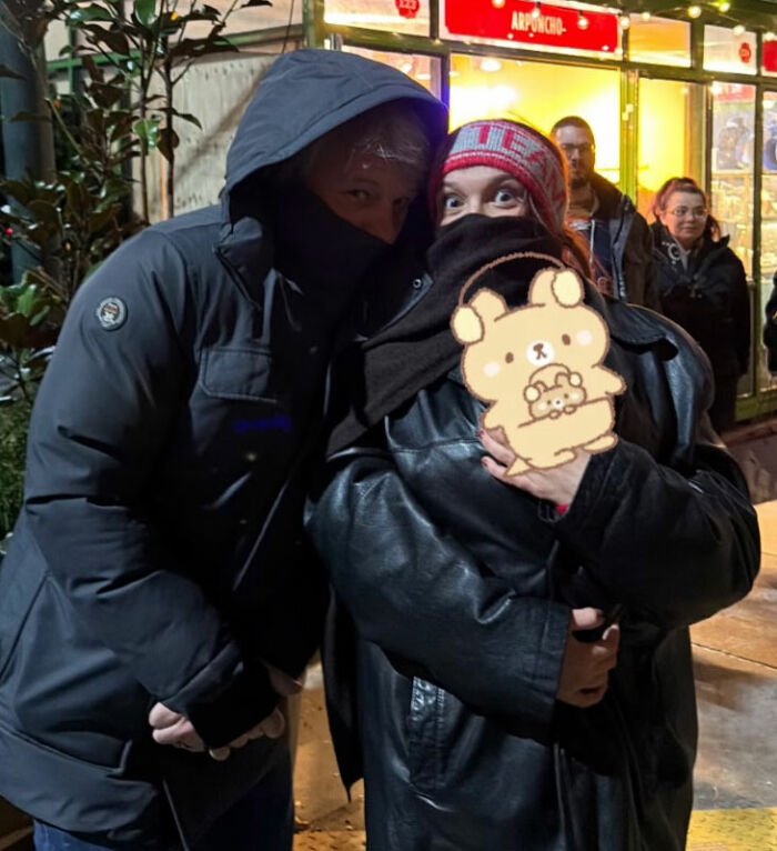 People outside a store at night with faces partially covered, linked to viral theory about Millie Bobby Brown’s newborn daughter.
