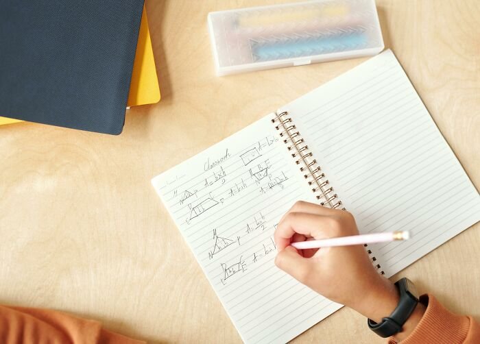 Student solving math problems in a notebook, illustrating a test challenge to beat the average U.S. student.