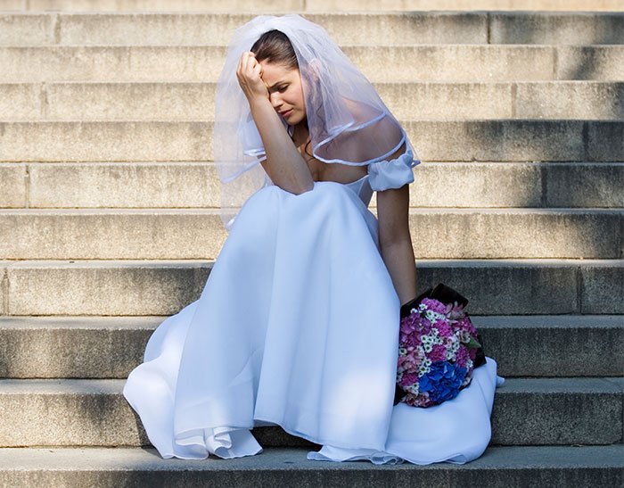 Bride sitting on steps looking upset, reflecting the impact of mom’s behavior ruining the wedding day.