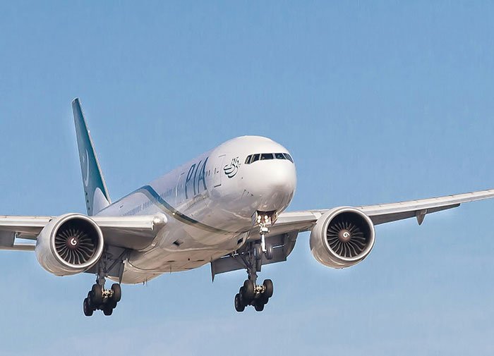 Commercial airplane approaching for landing under clear blue sky, related to woman breaking down in tears on flight.