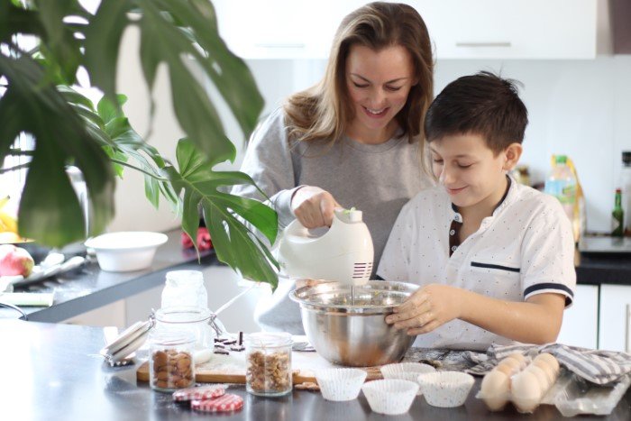 Woman bonding with son while baking in the kitchen, illustrating a moment related to man upset his ex blew up on girlfriend.