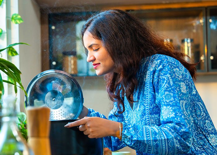 Woman in blue shirt checks the pot of chili in kitchen, reflecting on relationship after boyfriend salts entire pot.