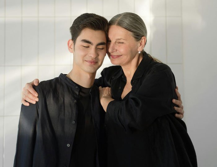 Woman smiling warmly while hugging her son, symbolizing being blinded by flowers, unaware of daughter’s efforts.