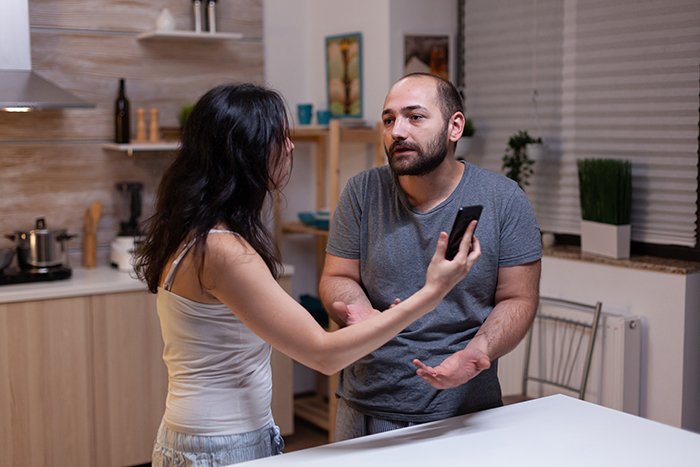 Woman sharing inspiring update after leaving cheating husband, speaking with a man in a modern kitchen setting.