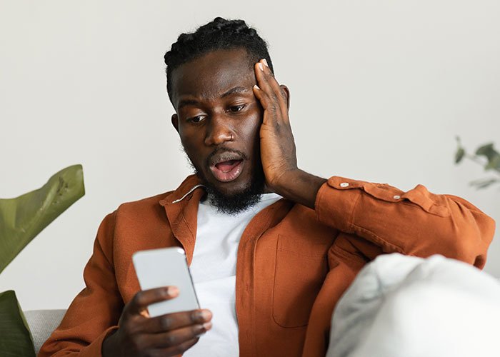 Man surprised and shocked looking at phone, reacting to unexpected message after fianc&eacute; disappeared years ago.