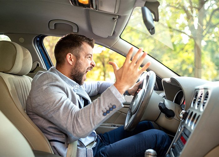 Angry man shouting inside car, expressing frustration, illustrating the concept of a male Karen by Gen Z.