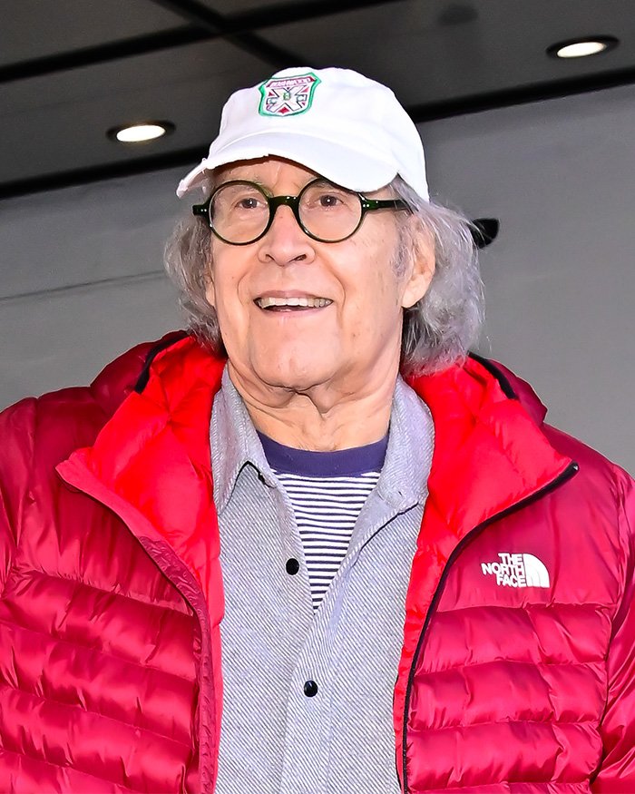 Older man wearing a white hat and red jacket smiling, related to Chevy Chase N-Word scandal and Community actress documentary.