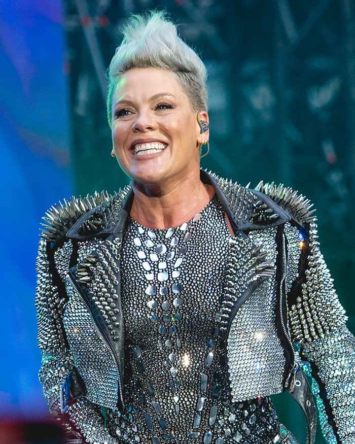 Pink smiling on stage wearing a studded outfit, breaking silence after spending New Year’s Eve alone in hospital.