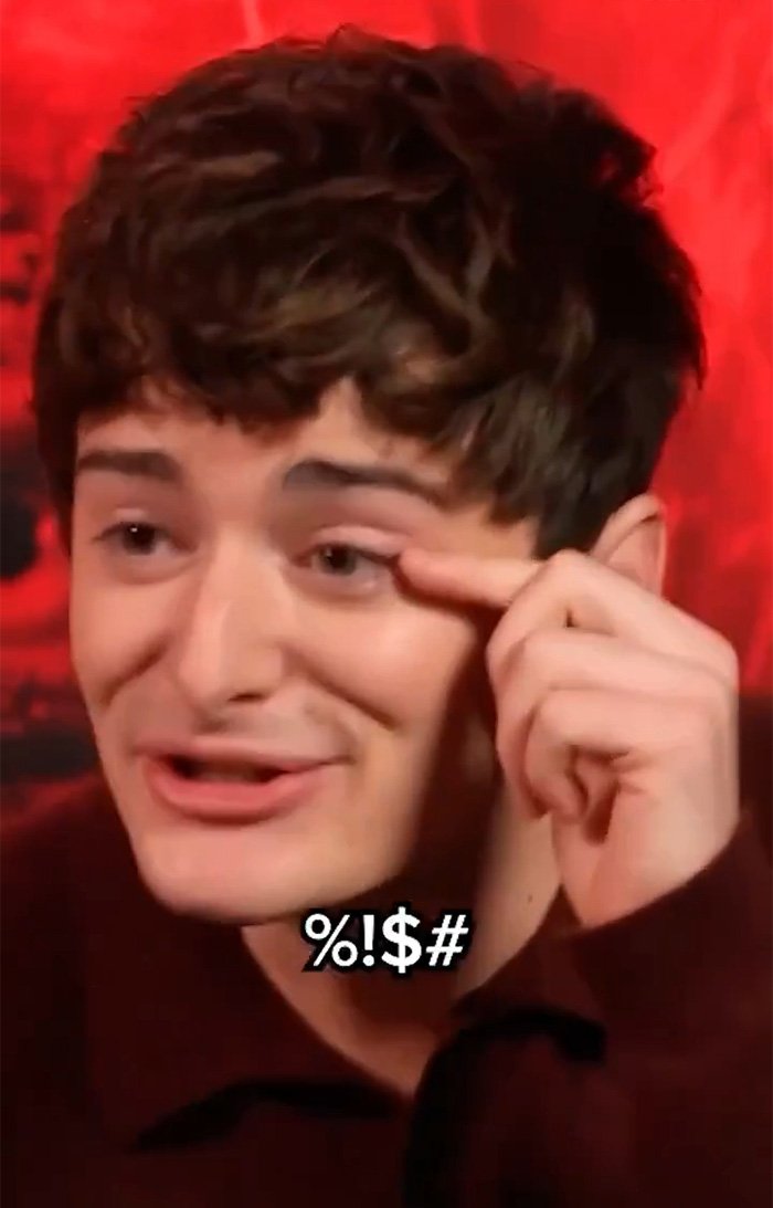 Noah Schnapp from Stranger Things making a facial gesture during an interview with a red background.