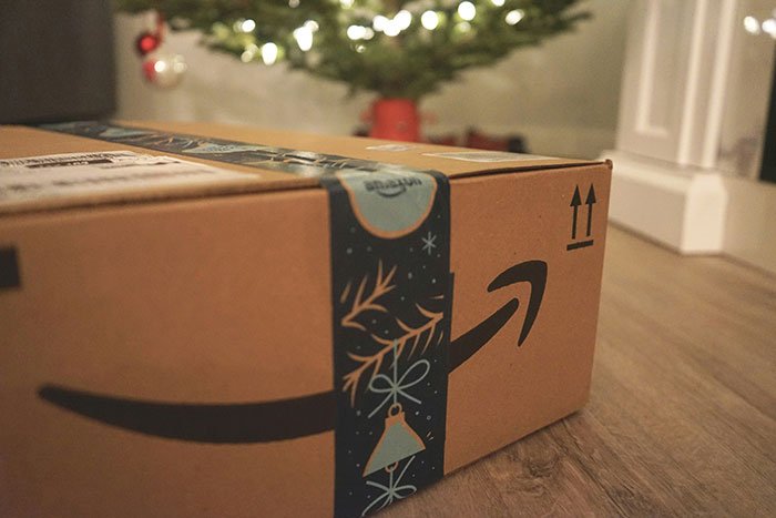 Close-up of a Christmas gift box from BF on the floor with a decorated tree in the background, woman confused about gifts.