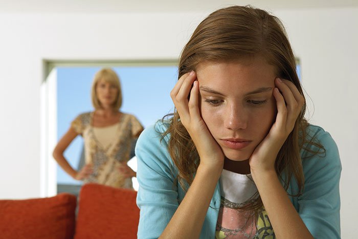 Teen girl looking upset while older woman stands in background, highlighting tension and crushed dreams during Christmas.