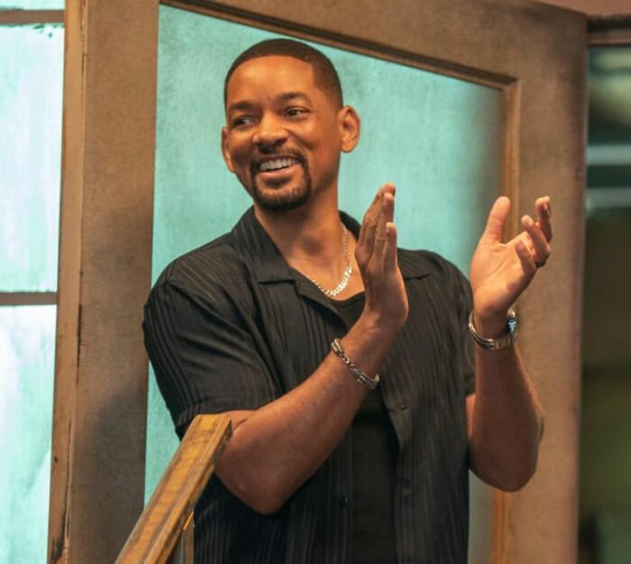 Will Smith smiling and clapping in a casual setting amid accusations involving harassment and grooming in a lawsuit.